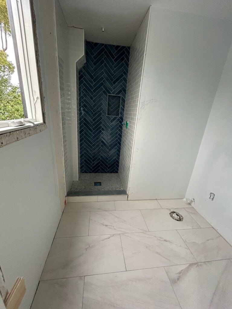 Modern shower installation with stylish dark herringbone tiles in bathroom remodeling.